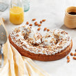 Large kringle with almonds on a marble surface with a glass of orange juice and a cup of coffee.