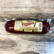 Rolled summer sausage with a label on a wooden surface