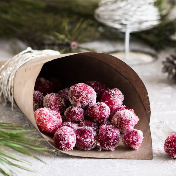 Candied Cranberries on a festive table with winter greens and pinecones
