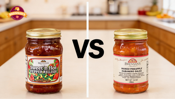 Brennan's Sweet 'n Hot Pepper Relish jar beside a Mango Pineapple Habanero Salsa jar with a large "VS" between them on a kitchen counter.