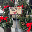 Holiday porch pots with red bows and a price sign at a store.