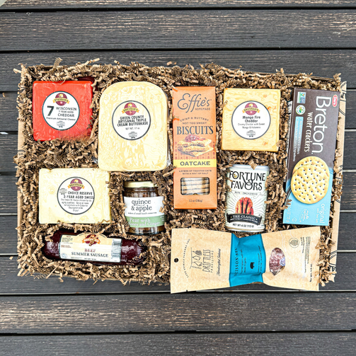 Gourmet gift box with various food items on a wooden surface
