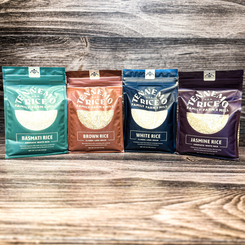 Four packages of Tenneva Rice Co. rice on a wooden surface